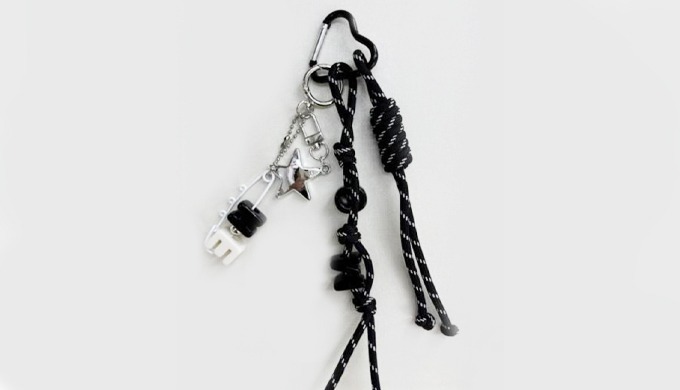 A modern keyring featuring black and silver-tone charms such as stars, camera, and alphabet letters....
