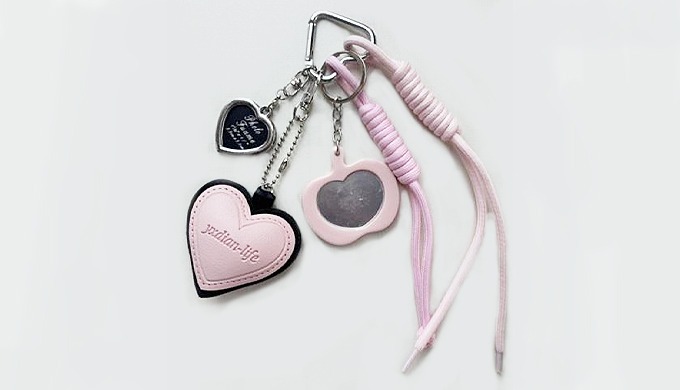 A cute apple-shaped charm keyring with a carabiner and strap, easy to attach to bags or keys. Availa...
