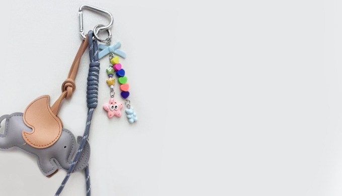 A cute elephant-shaped keyring with wing details, accented by colorful beads and ribbon charms. It a...