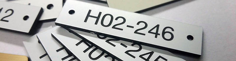 Lasergraverad plastlaminat. Levereras antingen med DH-tejp på baksidan eller med hål. Enstaka nummer...