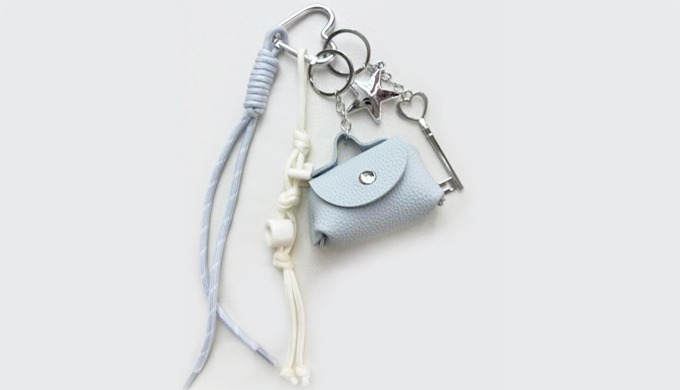A mini bag-shaped keyring with a carabiner and strap, easy to attach to bags or keys. Available in s...