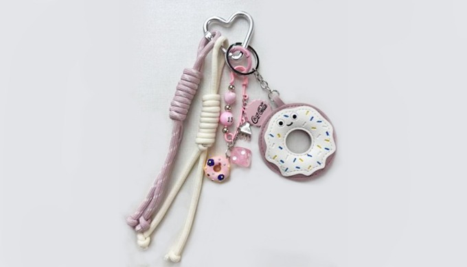 A playful character donut-shaped charm keyring with a carabiner and strap, perfect for attaching to ...