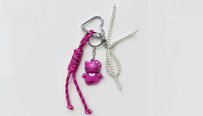 A charming cat-shaped keyring with pearl ribbon detail, complete with a carabiner and strap for easy...