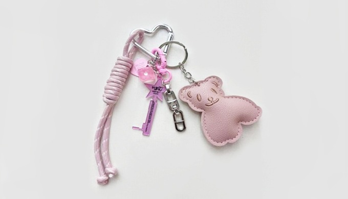 A soft bear-shaped charm keyring with a carabiner and strap, easy to attach to bags or keys. Availab...