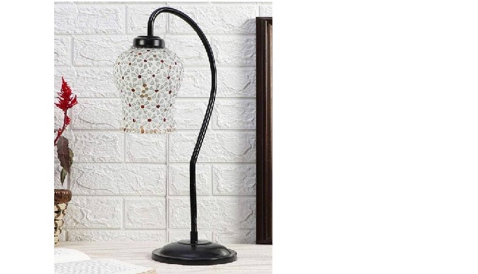 Mosaic table lamp with curved black stand and multicolor patterned glass shade placed on a wooden ta...