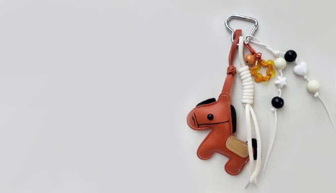 A cute horse-shaped charm keyring with a carabiner and strap, easy to attach to bags or keys. Accent...