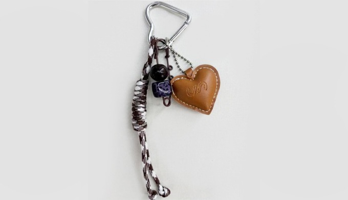 A keyring featuring a leather heart charm paired with key and bead details. Its natural and vintage ...