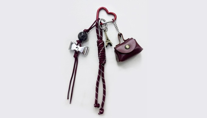 A mini handbag-shaped charm keyring with a carabiner and strap, perfect for attaching to bags or key...