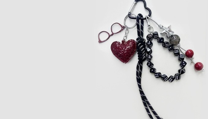 A stylish keyring featuring a padded heart charm with added details like glasses, stars, and beads. ...