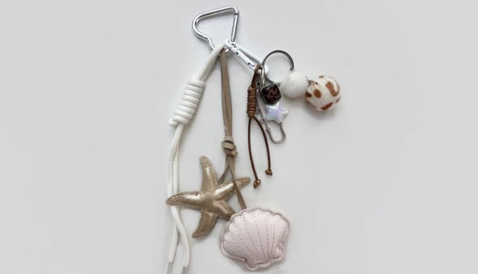 A keyring featuring ocean-inspired charms such as starfish and seashells, complete with a carabiner ...