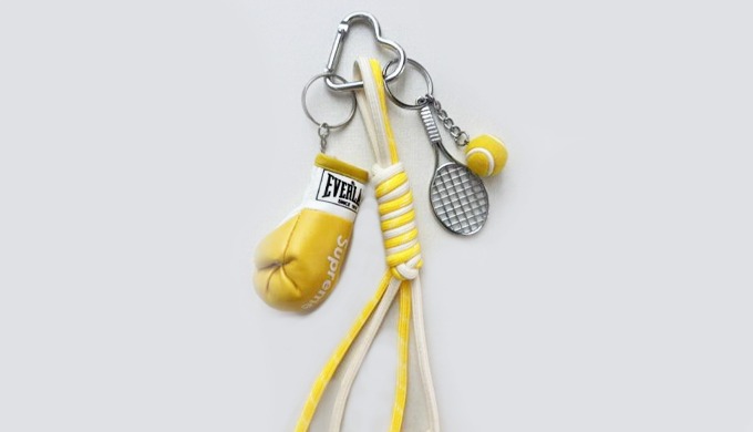 A playful keyring featuring sports-themed charms such as boxing gloves, tennis racket, and ball. Its...