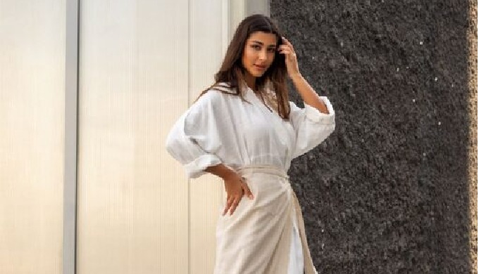 A white maxi dress with a trendy belt is part of a two-piece set. Modern modest attire is composed o...