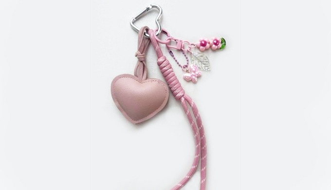 A charming keyring featuring a padded heart charm with added details such as ribbons, beads, and min...