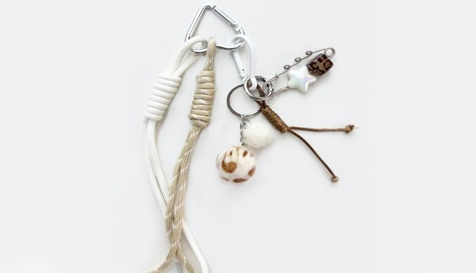 A keyring featuring marine and natural-inspired charms such as shells, fish, stars, and pom-poms. Pe...
